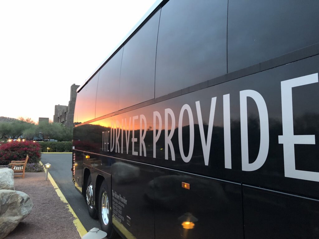 Black Driver Provider bus parked at sunset.