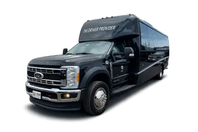 A black shuttle bus with tinted windows displays The Driver Provider on the front